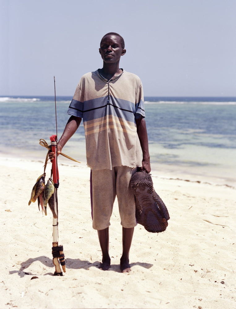 Saidi, a fisherman, standing on the sand at Tiwi Beach holding his catch, shot on the Intrepid Super 120